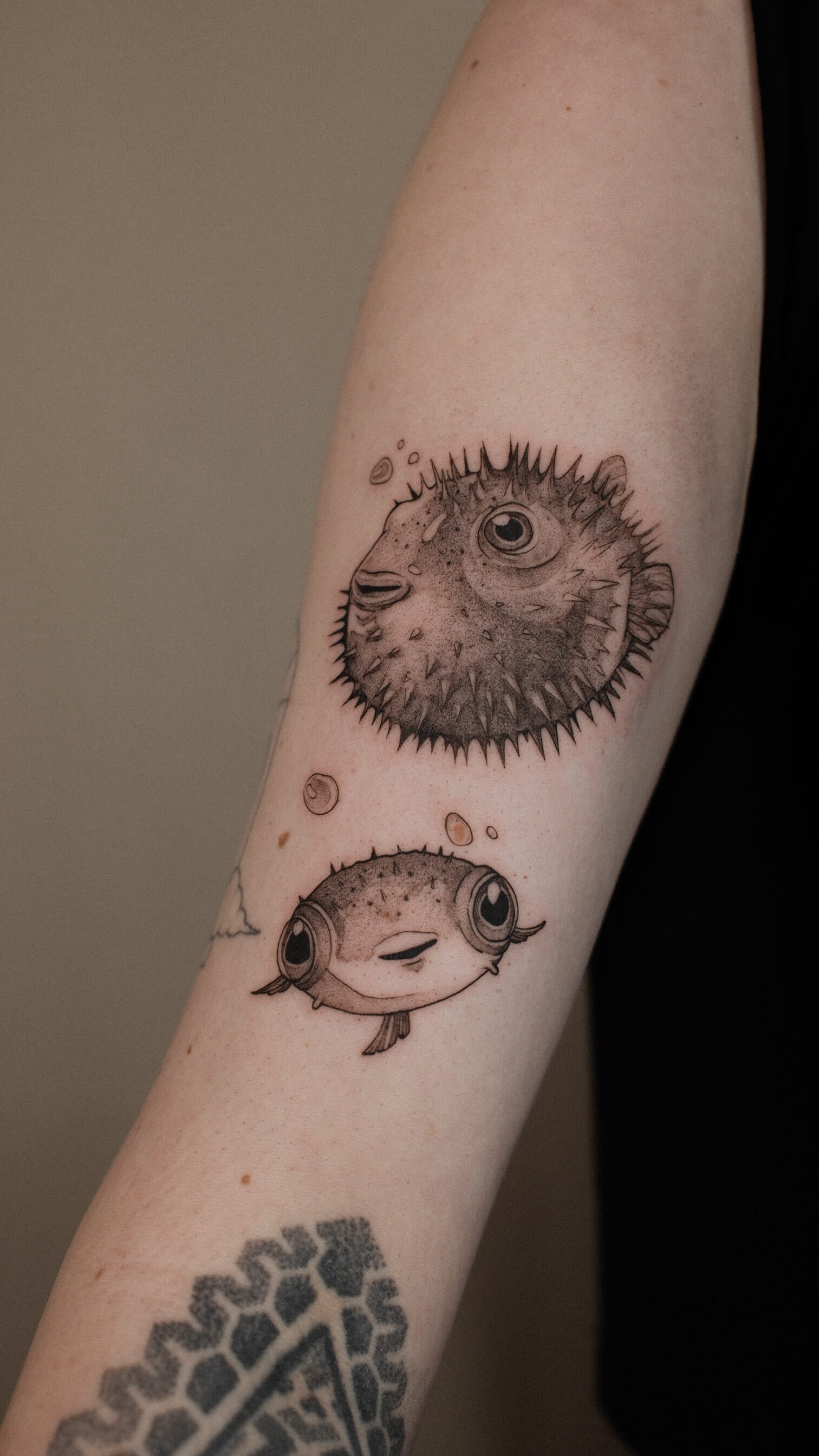 Graphic tattoo of two puffer fish on forearm — tattoo Barcelona