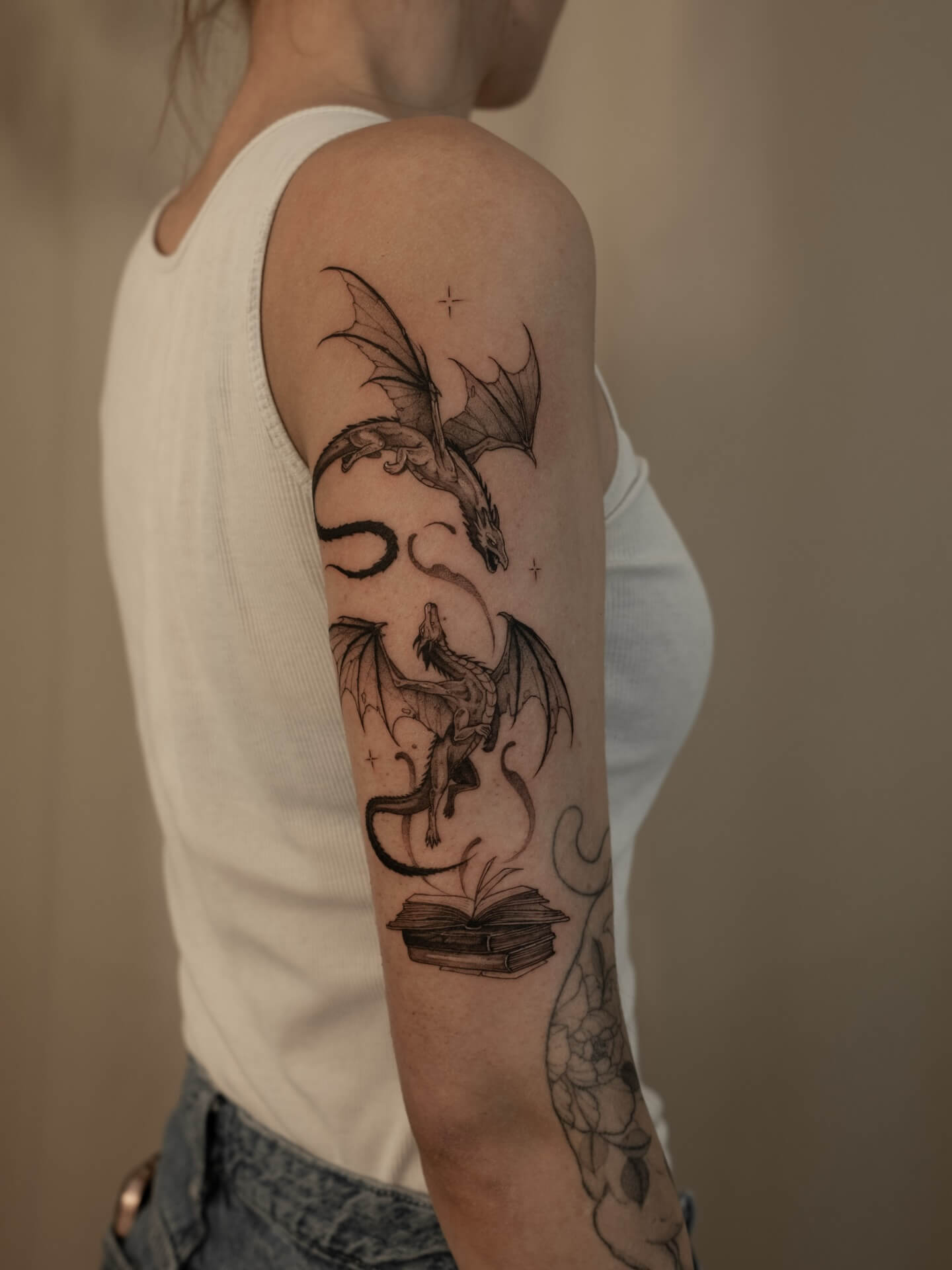 Sketch tattoo of two dragons emerging from open books on upper arm — tattoo Barcelona