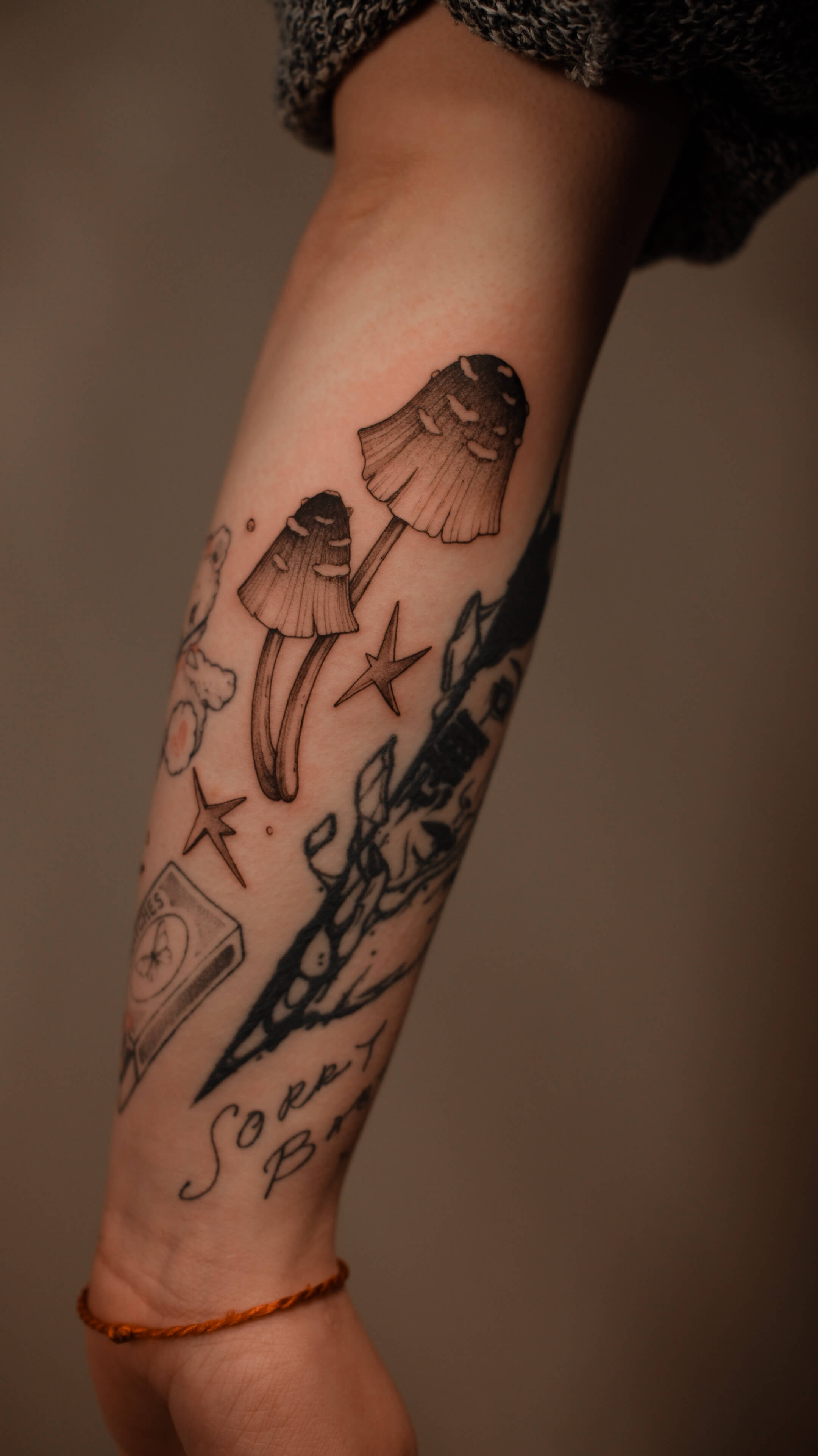 Sketch tattoo with mushrooms, stars and botanical elements on forearm — tattoo Barcelona