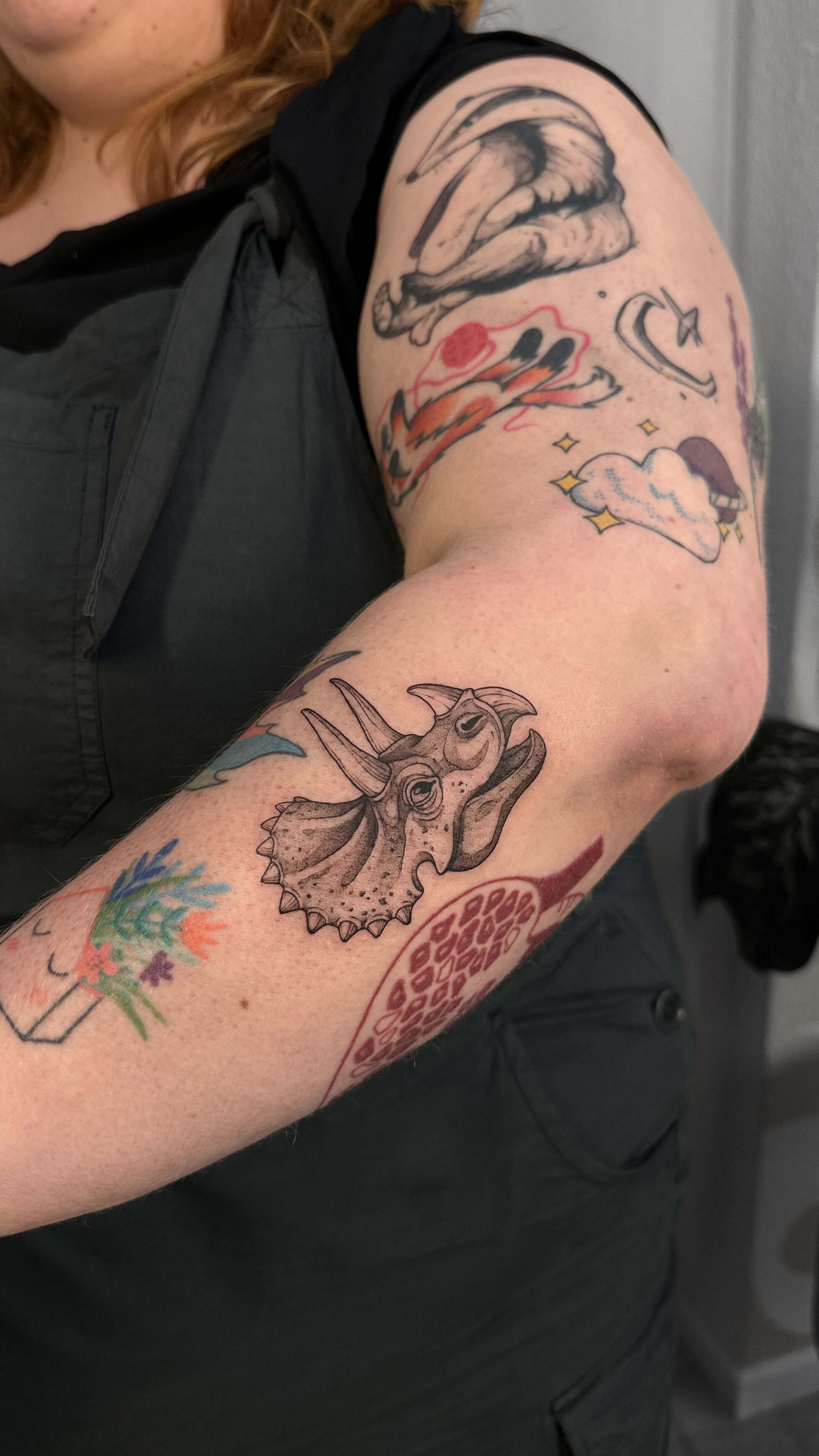 Graphic tattoo with triceratops and colorful botanical patchwork on arm — tattoo Barcelona
