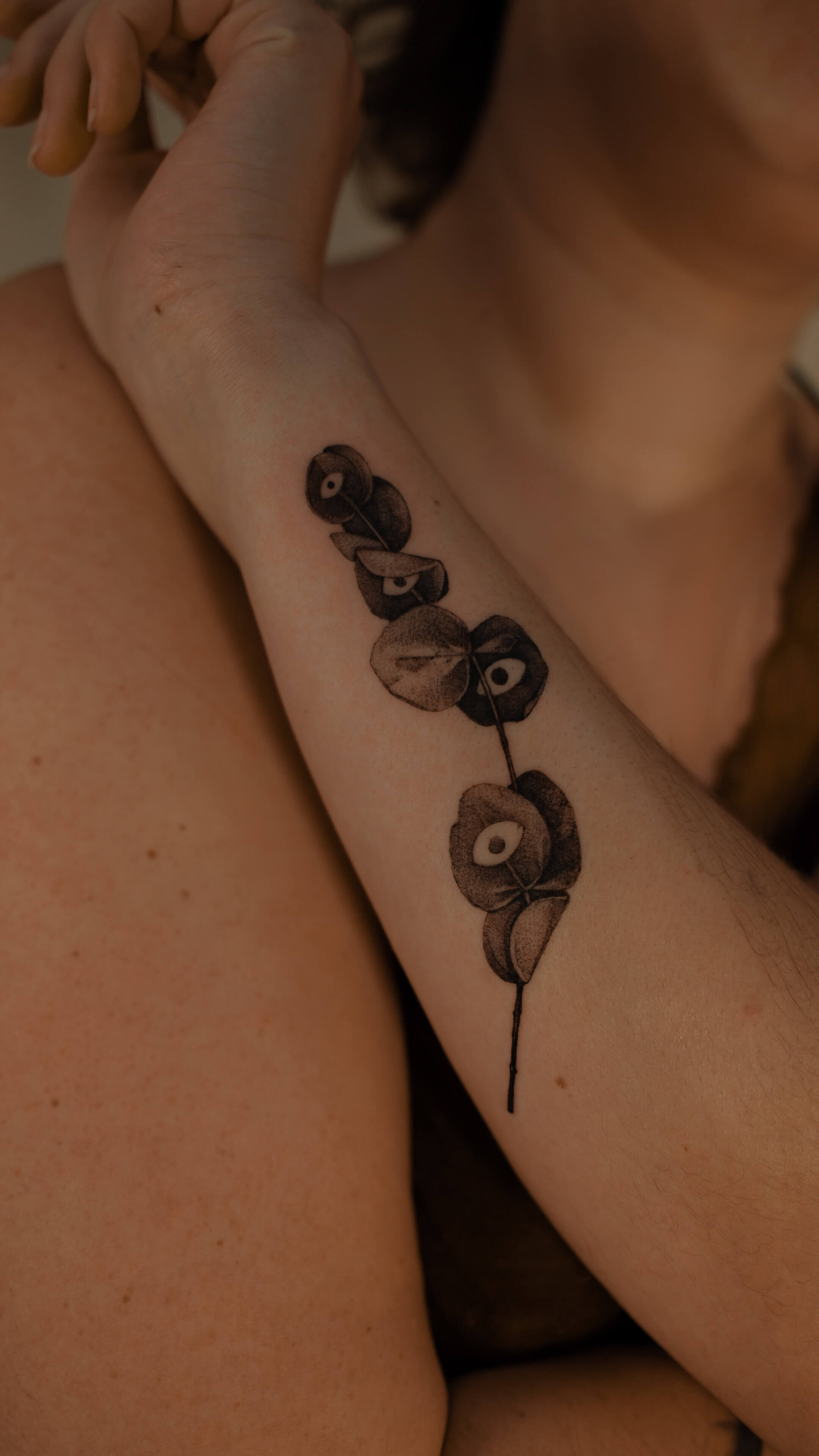 Fine line botanical tattoo with eucalyptus seed pods on inner arm — tattoo Barcelona